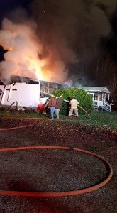 (Photo by Drakes Branch Volunteer Fire Department) Firefighters fight massive flames surrounded by billowing smoke that destroyed a Drakes Branch home on Saturday.