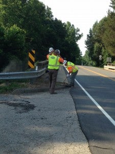 Virginia Department of Transportation workers remove excess dirt from a curb.
